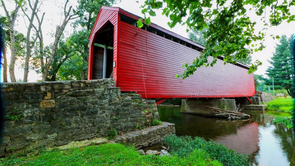 The bright red Roddy Road Covered Bridge spanning a creek near Thurmont, Maryland, USA