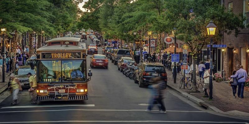 A person crossing the street in front of trolley in the King Street shopping and entertainment district of Alexandria, Virginia, USA.
