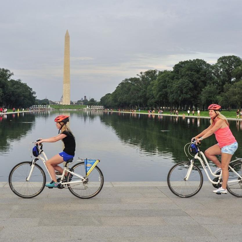 People biking past the Washington Monument on a tour with Bike &amp; Roll in Washington, DC, USA