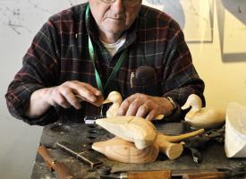 A man carves a duck decoy