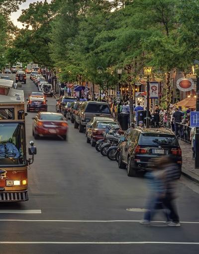 A person crossing the street in front of trolley in the King Street shopping and entertainment district of Alexandria, Virginia, USA.